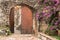 Wooden brown arched gate with stone wall