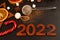 Wooden brown numbers 2022 on a dark background. There are stars carved out of wood, spices, scattered cocoa and a mug with