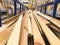 Wooden brown sawn natural building boards stick logs with knots on a rack on a sawmill in the store. The background