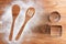 Wooden brown table dusted with flour and metal tins. Silhouette a two spoons of flour