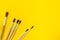 Wooden brushes for painting with paints on a yellow background