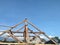 Wooden building frame of the old house was being repaired, against a backdrop of a bright blue sky