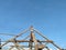 Wooden building frame of the old house was being repaired, against a backdrop of a bright blue sky