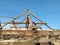 Wooden building frame of the old house was being repaired, against a backdrop of a bright blue sky