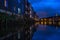 Wooden buildings reflecting on the Nidelva River under a cloudy sky in the evening in Trondheim