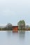 Wooden cabin, building on pond shore in rain moody weather. Long exposure, Czech landscape