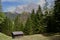 Wooden cabin in a green land surrounded by beautiful green trees and high rocky mountains