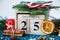 Wooden calendar with 25 December date in it on green place mat, candle, fir tree, dried oranges, pines. Christmas celebration