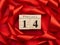 Wooden calendar with date 14 february on a on a red background with a twisted red silk ribbon