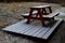 Wooden camping bench sitting behind a cottage on a small planted terrace. snowy with snow. table made of planks and beams