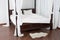 Wooden canopy bed and a white hide on the floor