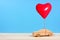 Wooden car with red heart balloon against blue background