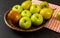 Wooden carved bowl with apples and pears with red chequered tablecloth on black board