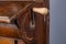 The wooden case of a scratched old apparatus with a handle. Brown shabby wooden telephone on a gray isolated background