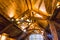 Wooden ceiling and vintage chandelier with electric bulbs. Classic luxury home architecture