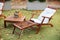 Wooden chair in autumn garden. Vintage radio on table. Wooden deckchair on green summer lawn on picnic. Lounge sunbed. Wooden gard