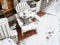 A wooden chair with a bucket with a yellowed coniferous plant stands strewn with snow outside