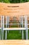 Wooden chairs stand outside in the park in the rain. Empty auditorium, green grass, waterdrops, closeup