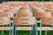 Wooden chairs stand outside in the park in the rain. Empty auditorium, green grass, waterdrops, closeup