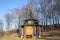 A wooden chapel surrounded by bare trees against a sky