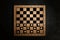 Wooden checkerboard with game pieces on black table, top view