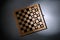 Wooden checkerboard with game pieces on grey background, top view