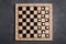 Wooden checkerboard with game pieces on grey table, top view