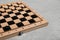 Wooden checkerboard with game pieces on light grey table, closeup