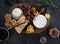 Wooden cheeseboard on slate surface with a variety of cheeses, crackers, fruit, honey, rosemary sprigs and chutney
