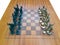 A wooden chess board with metal figurines top view