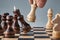 Wooden chess pieces on a chessboard, a hand with a white queen makes a move, the concept of strategy, planning and decision making