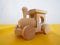 Wooden children`s toy locomotive is standing on yellow mats against the background of a white wall