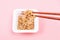 Wooden chopsticks holding japanese natto beans on pink background top view