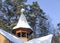 Wooden Christian bell tower with a dome and a cross covered with snow in the forest in winter