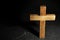 Wooden Christian cross on black slate table against background, above view with space for text. Religion concept