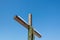 Wooden christian cross with green wreath and blue yellow ribbons on the plain blue sky background, Concept of hope