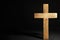 Wooden Christian cross on slate table against dark background, space for text. Religion concept