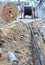 Wooden coil of electric cable and optical fibers in the digging on the street construction site