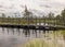 A wooden construction walking bridge in the middle of the swamp. View of the beautiful nature in the swamp - a pond, conifers,