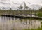 A wooden construction walking bridge in the middle of the swamp. View of the beautiful nature in the swamp - a pond, conifers,