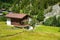 Wooden cottage house on green fields in canton of Valais, Switzerland in summer.