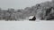 Wooden cottage in mountain village during snow falling