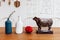 Wooden cow sculpture with cut of meat beef of diagram on it with blue, white jar and red fruit on wooden table