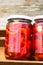 Wooden crate with glass jars with pickled red bell peppers.Preserved food concept, canned vegetables isolated in a rustic