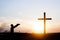 Wooden cross against the sky. The silhouette of the cross. A man is praying with his hands up. Motiveva on her knees. Sunset