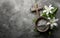 Wooden cross, ashes bow, and lily flowers branch on concrete stone background. Faith, liturgy, funeral, .cremation, religious