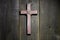 Wooden cross hanging on rustic wooden background