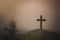 A wooden cross on a mound The background of the setting sun is about to set. Christian religious concepts, crucifixion of faith