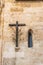 Wooden cross with olive branch next to a Gothic window. Church of Sineu