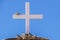 Wooden cross on roof against very blue sky with pigeons perching on it and below - close-up